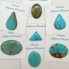 turquoise colored stones are arranged in rows on white paper with blue writing underneath each stone