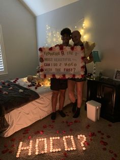 two people standing in front of a bed holding a sign that says, mom's