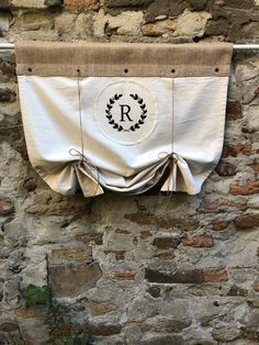 an old stone wall with a curtain hanging from it's side and a monogrammed wreath on the front