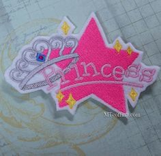 a pink and gold princess patch sitting on top of a piece of paper