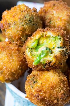 some fried food in a white bowl on a table with broccoli florets