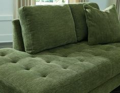 a green couch with two pillows on it