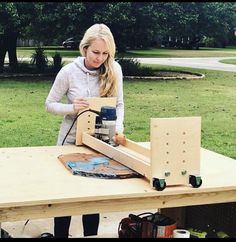 a woman is working on a project at a table in the park with other people