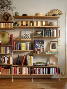 a bookshelf filled with lots of books on top of wooden shelves next to a wall