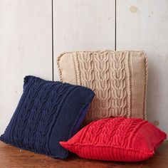 two knitted pillows sitting on top of a wooden table