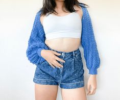 a young woman is posing with her hands on her hips and wearing blue denim shorts