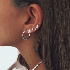 a woman wearing silver earrings and a chain around her neck with the word love written on it