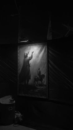 a black and white photo of a painting in a dark room with a light shining on it