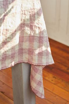 a pink and white checkered table cloth draped over a metal pole on a wooden floor