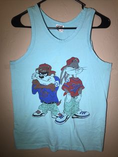 Very nice vintage tank top. Light blue in color. Has some light spots that may come out with some effort. Pit to pit 17.5”. Pit to bottom hem 16.5”. Top of shoulder to bottom hem 25”. Shoulder opening to pit opening 9”. Vintage clothes Any measurements given will be approximate only. Measurements are obtained using a tailor’s tape and subject to slight variance. All vintage clothes are sold “as-is” with no refunds given and no returns accepted. Zoom in on all photos to see the item’s actual cond Blue Graphic Print Muscle Tee, Blue Casual Muscle Tee With Graphic Print, Retro Crew Neck Tank Top With Graphic Print, Retro Graphic Print Tank Top, Retro Graphic Print Tank Top For Summer, Vintage Tank Top For Spring Streetwear, Y2k Sleeveless T-shirt For Spring, Vintage Tank T-shirt For Summer, Retro Graphic Print Tank Top For Streetwear