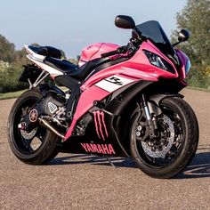 a pink motorcycle parked on the side of a road