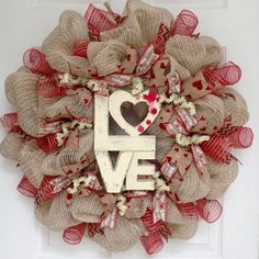 a wreath with the word love written on it in front of a door decorated with burlap and ribbon