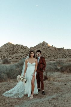 a bride and groom standing in the desert