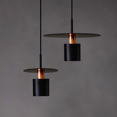 three lights hanging from the ceiling in a room with grey walls and concrete flooring