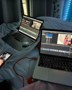 two laptops sitting on top of a bed next to each other with remote controls