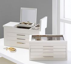 two white jewelry boxes sitting on top of a table next to each other with their lids open