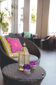 a wicker chair with two candles on it and a decorative pillow in the background