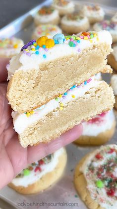 a hand holding a half eaten cookie with white frosting and sprinkles