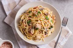 a white bowl filled with pasta and meat on top of a checkered table cloth