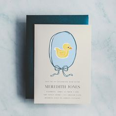 a card with a rubber ducky in an egg on it's back, sitting on a marble surface