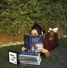 a woman laying on the grass holding up a book