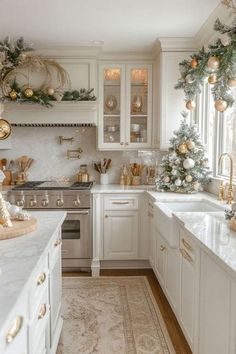 a kitchen decorated for christmas with white cabinets and gold ornaments