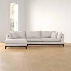 a white couch sitting on top of a hard wood floor next to an open window