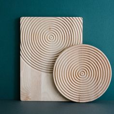 two wooden plates sitting next to each other on top of a table in front of a green wall