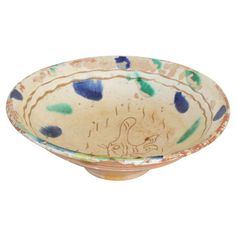 a bowl with blue, green and orange designs on the rim is sitting in front of a white background