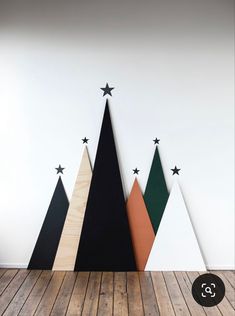 three wooden christmas trees with black and white stars on them, against a white wall