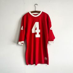 Nice red football jersey from the 70s. Small well done repair on back, and some small spots of wear shown in photos, but overall solid. Measurements: Pit to Pit: 22 inches Shoulder to Waist: 32 inches Retro Red Top For Game Day, Red Retro Top For Game Day, Vintage Sports Tops For Football Season, Red Football Jersey, Number 4, Well Done, Denver Co, The 70s, May 7