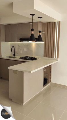 an empty kitchen with white counter tops and black pendant lights