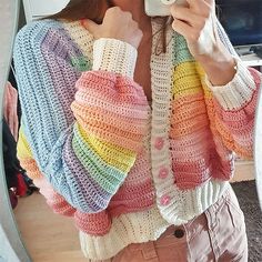 a woman taking a selfie in front of a mirror wearing a colorful crochet sweater