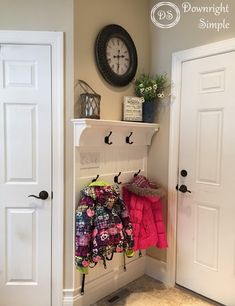 a coat rack with coats hanging on it and a clock in the corner behind it