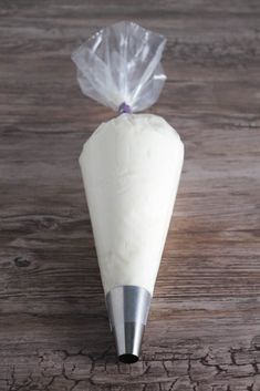 a pastry cone with a plastic bag on it sitting on a wooden table next to a knife