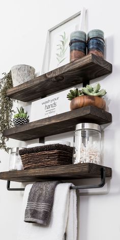 two wooden shelves with towels, plants and other items on top of them in front of a mirror