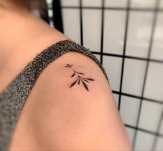 a woman's arm with a small tattoo design on the left side of her shoulder