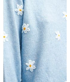 a blue sweater with white daisies on the front and bottom, as seen from above