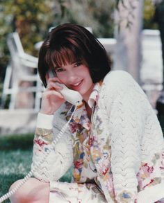 a woman sitting on the grass talking on a phone