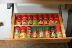 several spice jars sit in a drawer on a counter top next to a wooden table