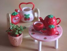 there is a toy tea set on the table with potted plants next to it