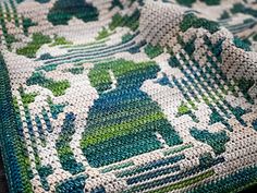 a green and white crocheted blanket sitting on top of a table