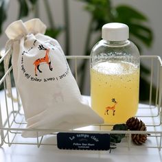 a bottle of liquid next to a drawstring bag and pine cone on a table