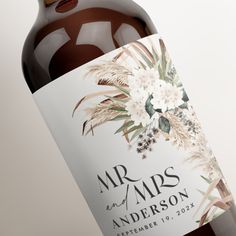 a bottle of wine that is sitting next to a white tablecloth with flowers on it