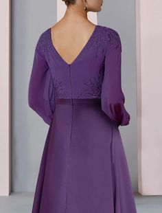 the back of a woman's purple dress with long sleeves and an open v - neck