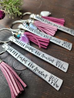 four keychains with different sayings on them sitting on a table next to a flower