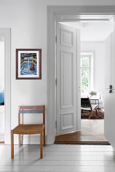 an open door leading to a living room with white walls and wood flooring on either side