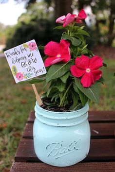 a blue mason jar filled with pink flowers on top of a wooden table