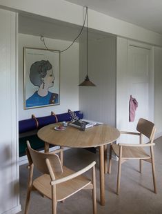 a dining room table with chairs and a painting on the wall