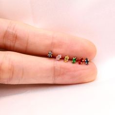 a person's hand with four different colored stones on their thumb and one is wearing a ring